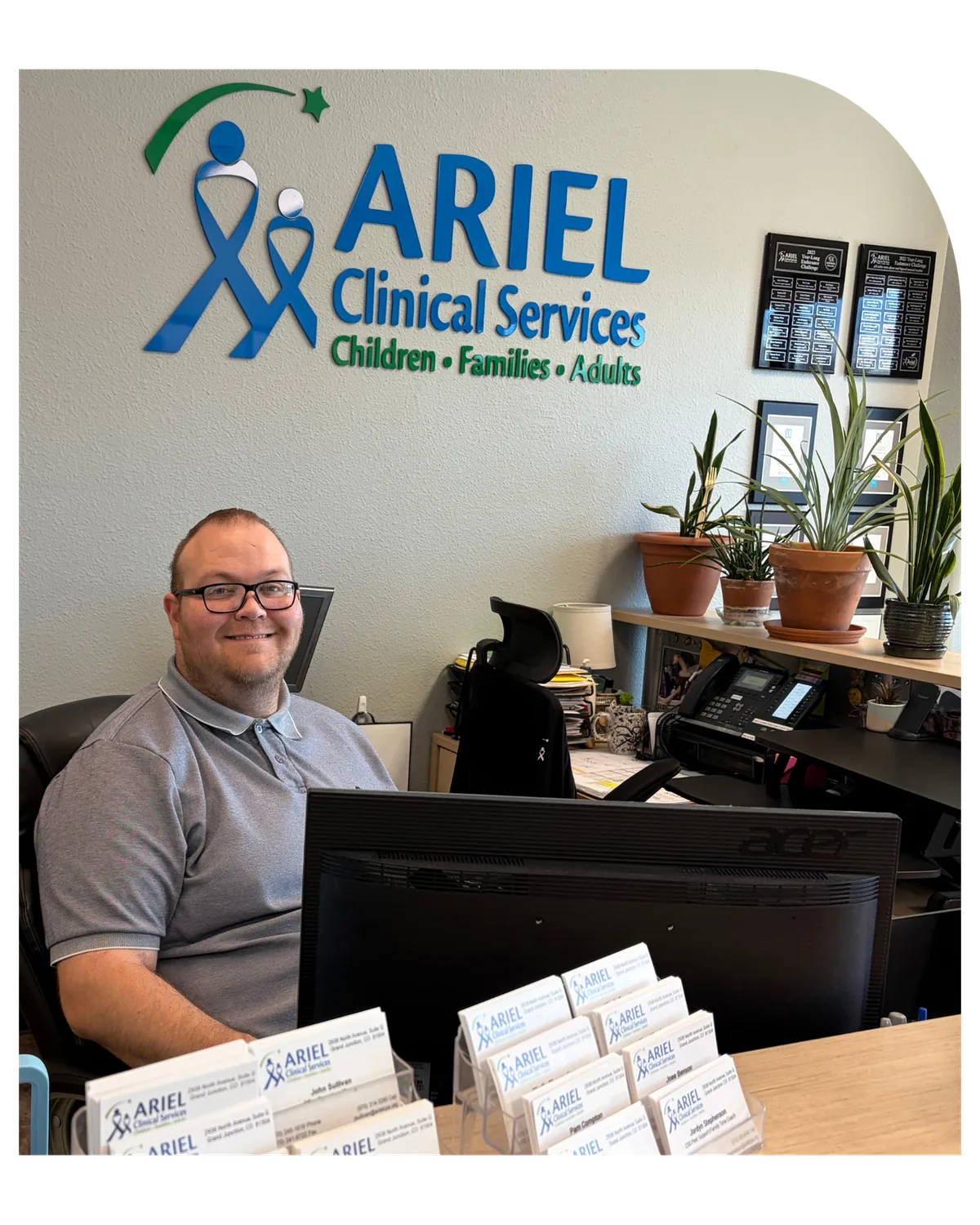 Staff member at the front desk of Ariel’s Grand Junction office, under the Ariel Clinical Services sign