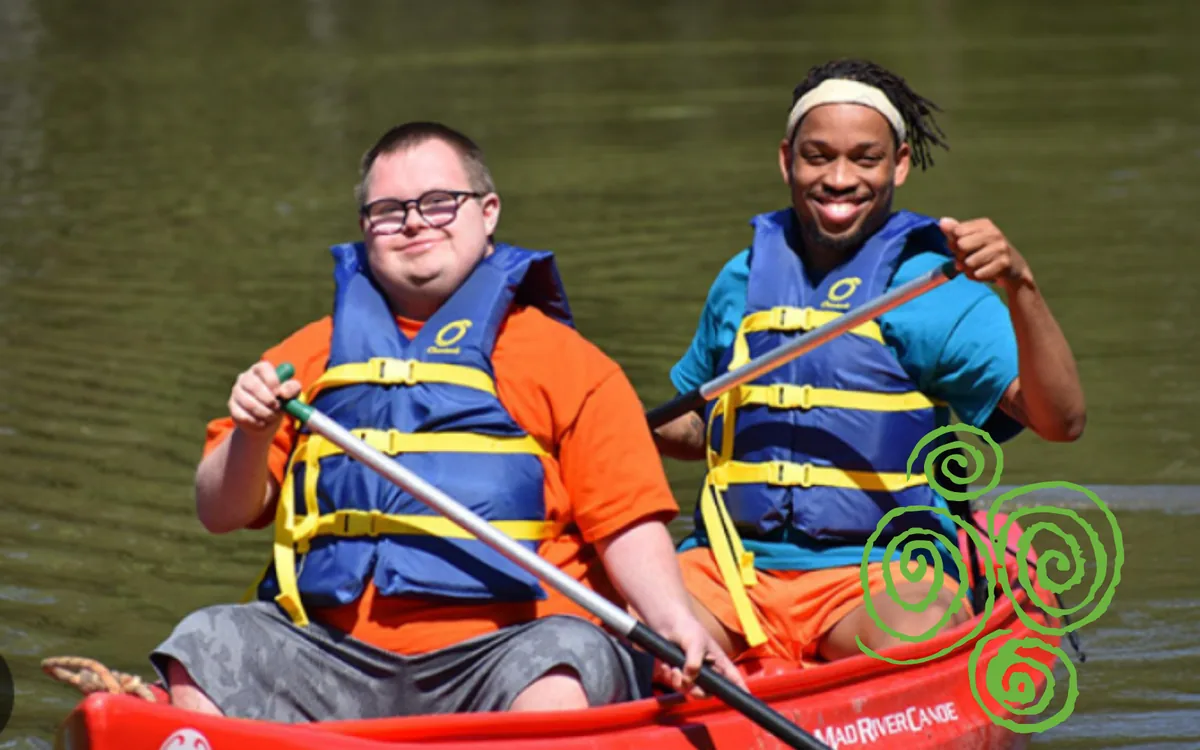members-canoeing Two men in life jackets smile as they paddle a red canoe.