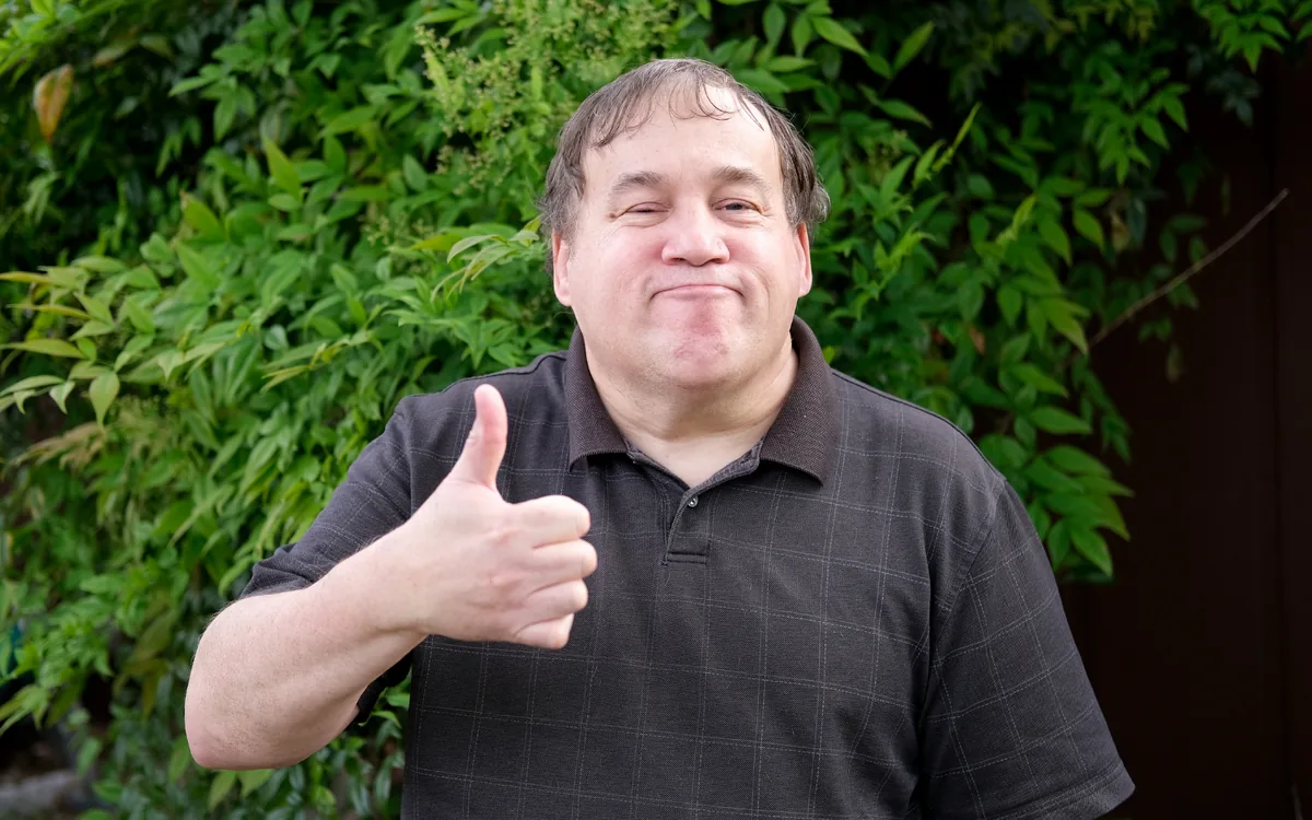 A smiling man gives a thumbs up.