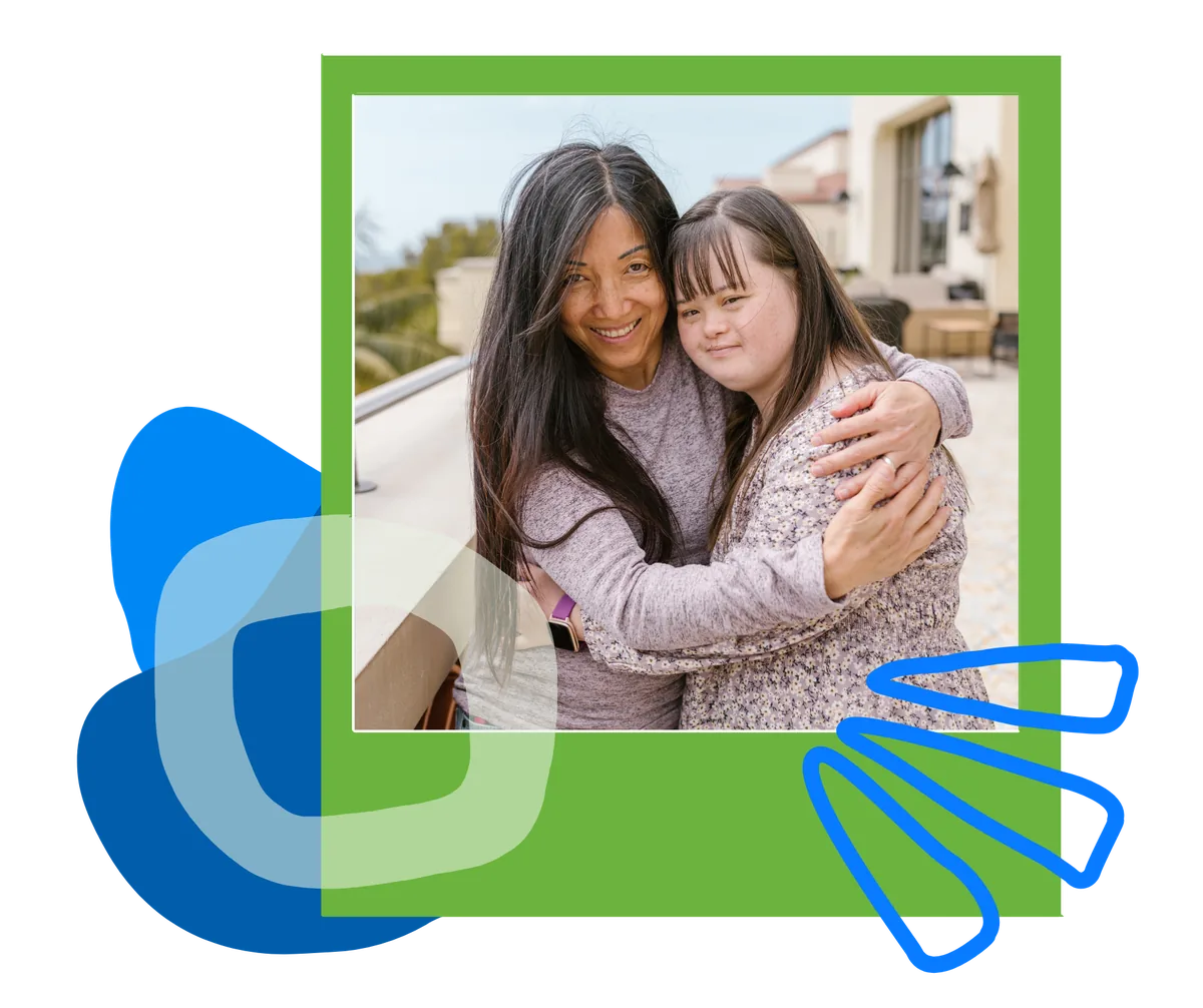 A woman and a young woman share a hug on a sunny patio.