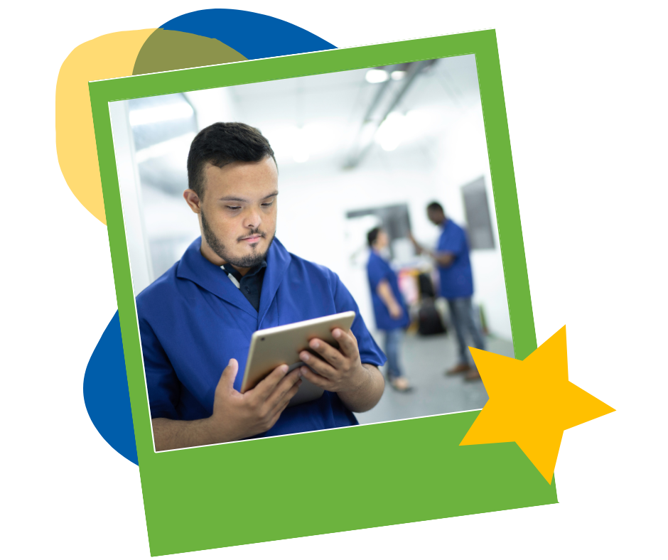 A young man in a blue work uniform reading a tablet on the job, with coworkers behind him